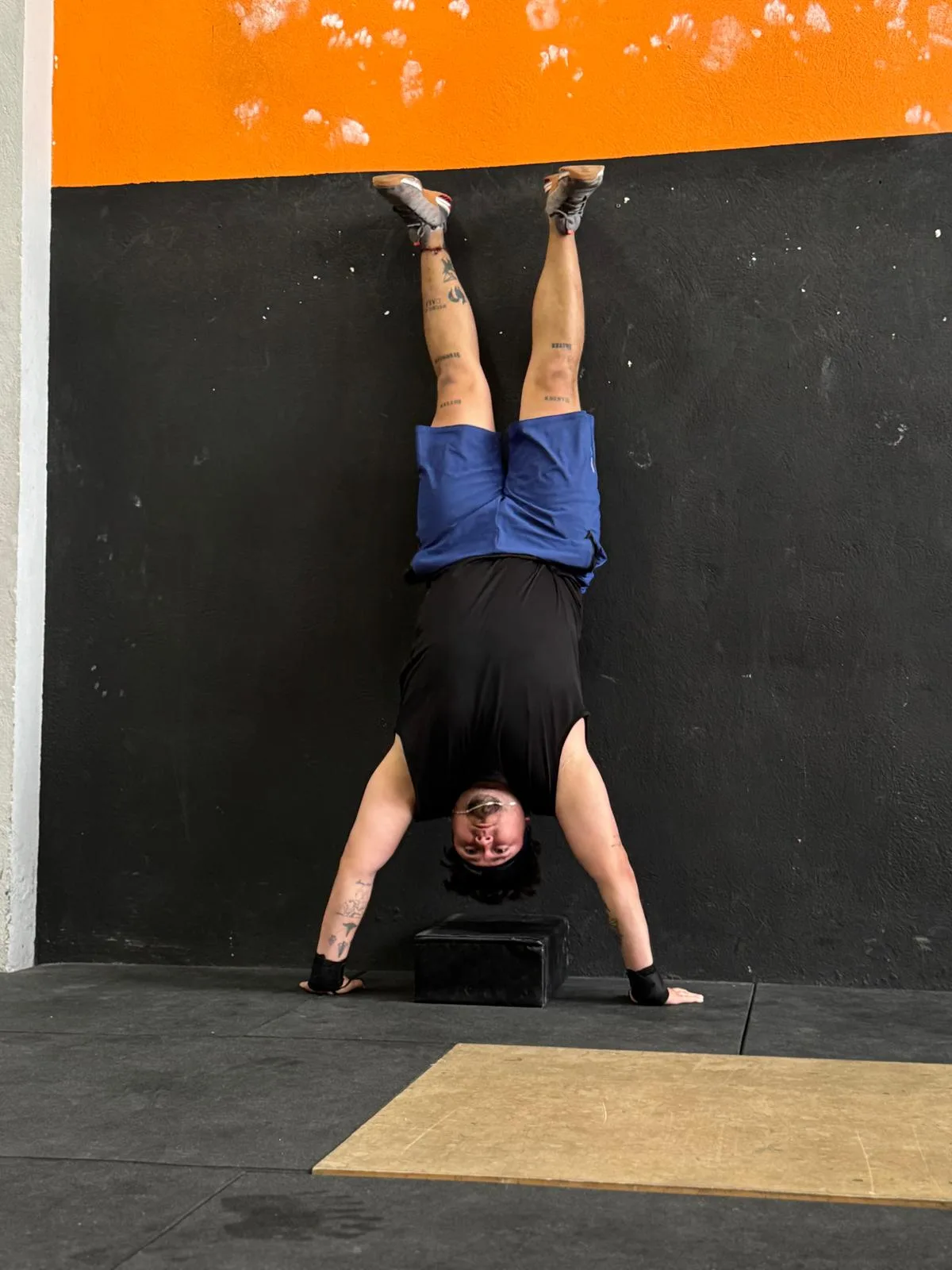 Atleta femenina realizando handstand push-up contra la pared en Taronja Box